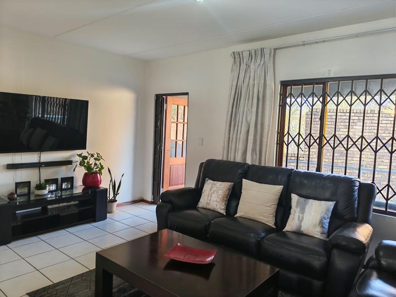 A living room featuring tiled flooring and a sliding door with security gate, providing access to the exterior.