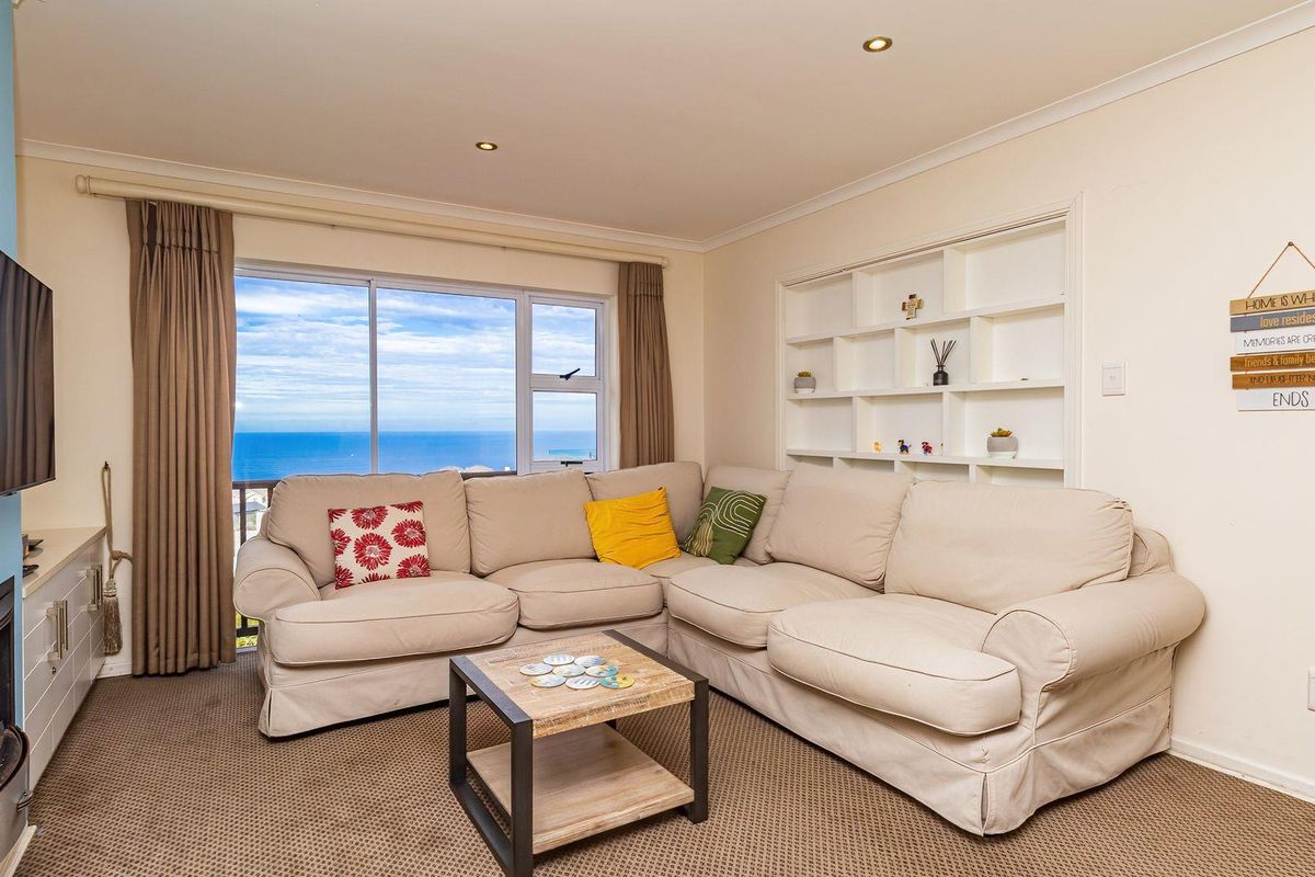 A comfortable living room featuring a built-in fireplace, recessed shelving, and large windows offering expansive ocean views.