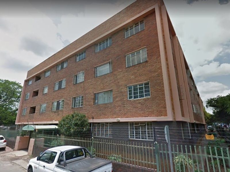 Exterior view of a multi-story apartment building featuring a classic face brick facade and steel-framed windows.
