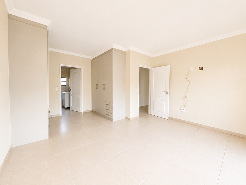 A bright, spacious bedroom featuring neutral tiled flooring, built-in cupboards, and clean finishes, offering a versatile blank canvas for personalization.