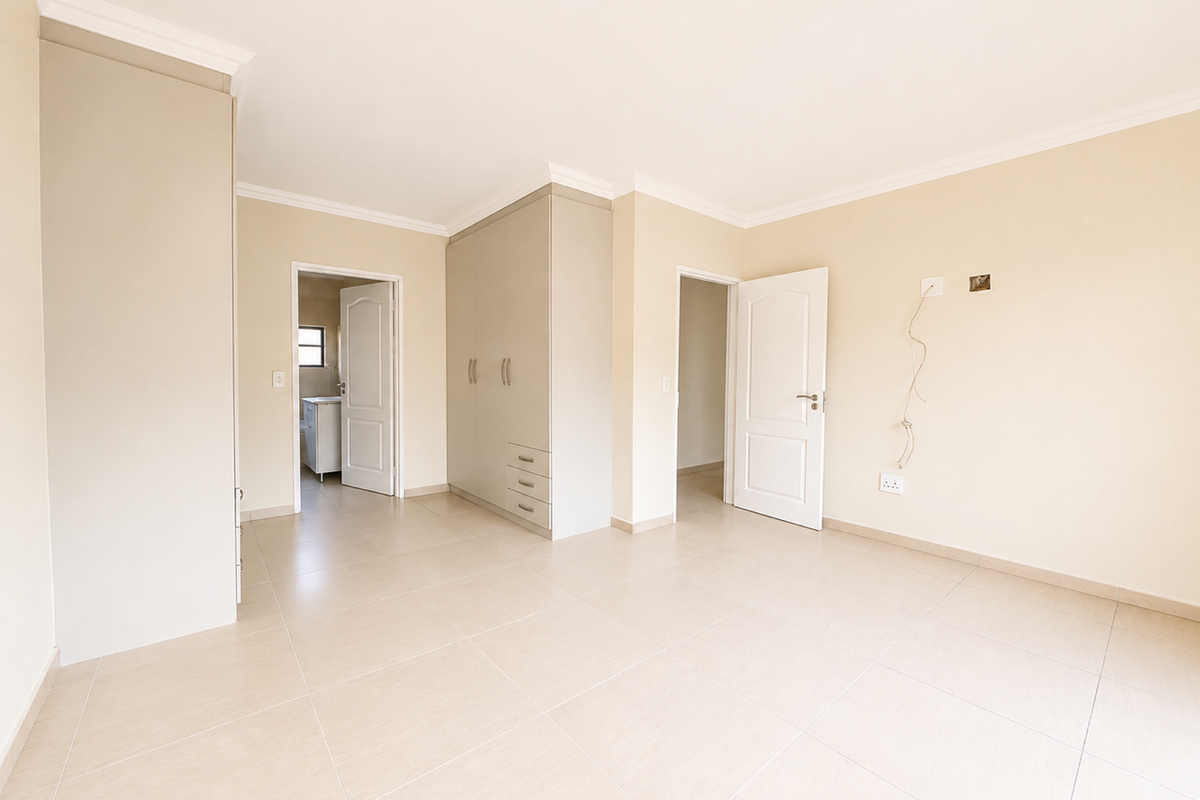 A bright, spacious bedroom featuring neutral tiled flooring, built-in cupboards, and clean finishes, offering a versatile blank canvas for personalization.
