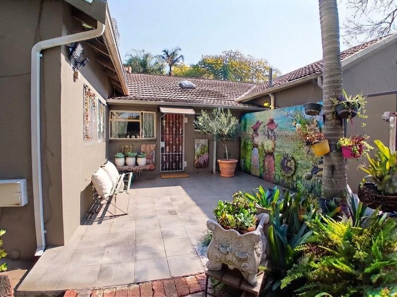 A private paved patio area featuring tiled flooring, a security gate, and a decorative mural on the boundary wall, offering a pleasant outdoor space.