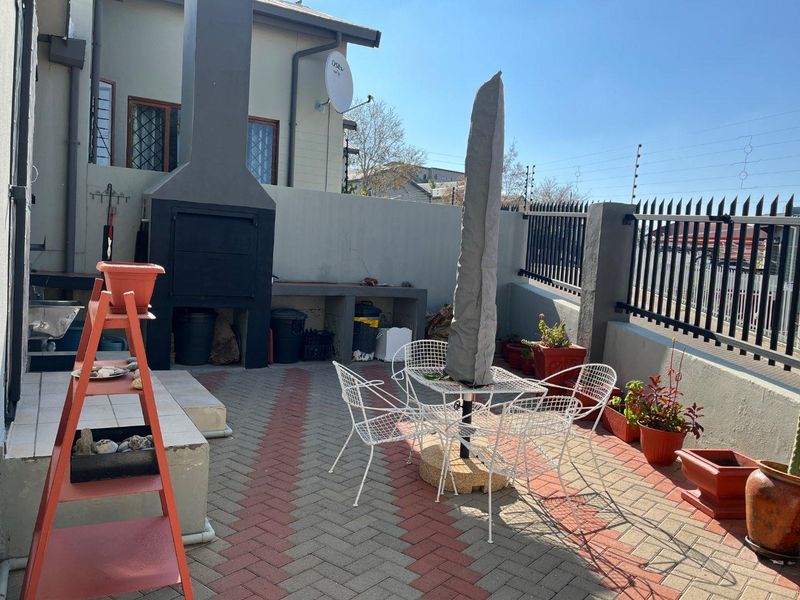 Outdoor patio area featuring a built-in braai, paved flooring, and secure perimeter walling, providing a functional space for outdoor entertaining.