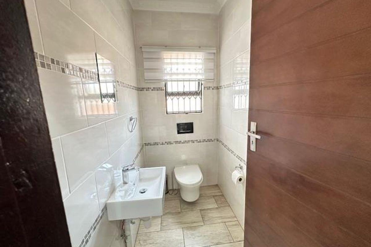 A modern guest bathroom featuring floor-to-ceiling wall tiles, a wall-mounted basin, and a sleek wall-hung toilet.