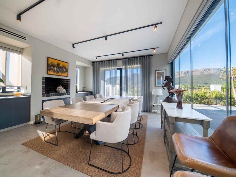 Modern dining room featuring a built-in fireplace, sleek track lighting, and expansive glass sliding doors offering scenic mountain views.