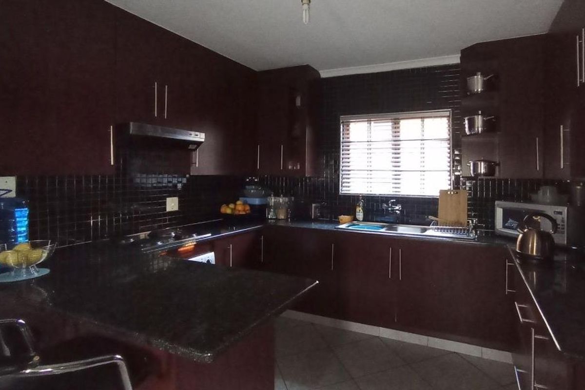 A functional kitchen featuring dark cabinetry, granite countertops, a tiled backsplash, and a built-in extractor fan.