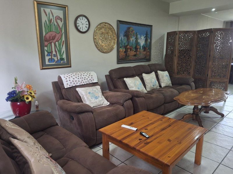A comfortable living room featuring neutral walls, tiled flooring, and recessed ceiling lighting, providing a functional and well-lit space for relaxation.