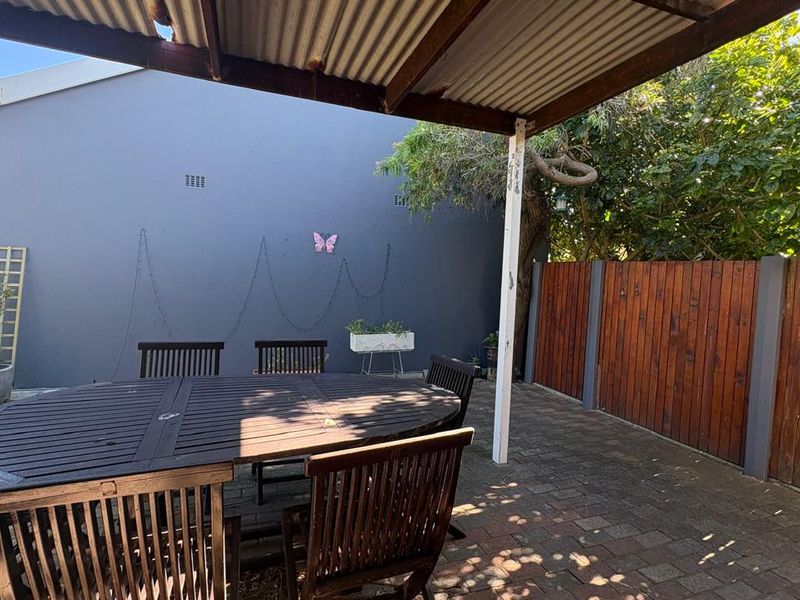 Covered outdoor patio area featuring brick paving, a corrugated iron roof, and a private timber fence boundary.