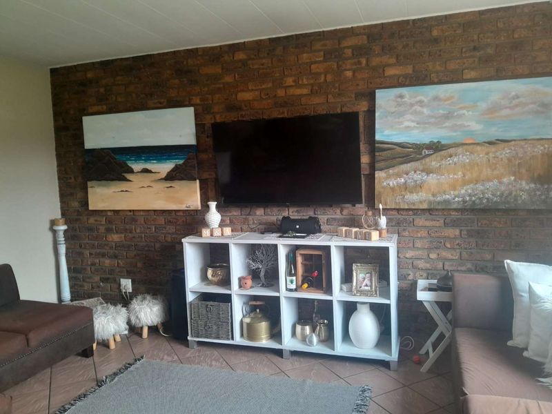 A living room featuring a prominent exposed brick feature wall and tiled flooring, providing a rustic foundation for the living space.