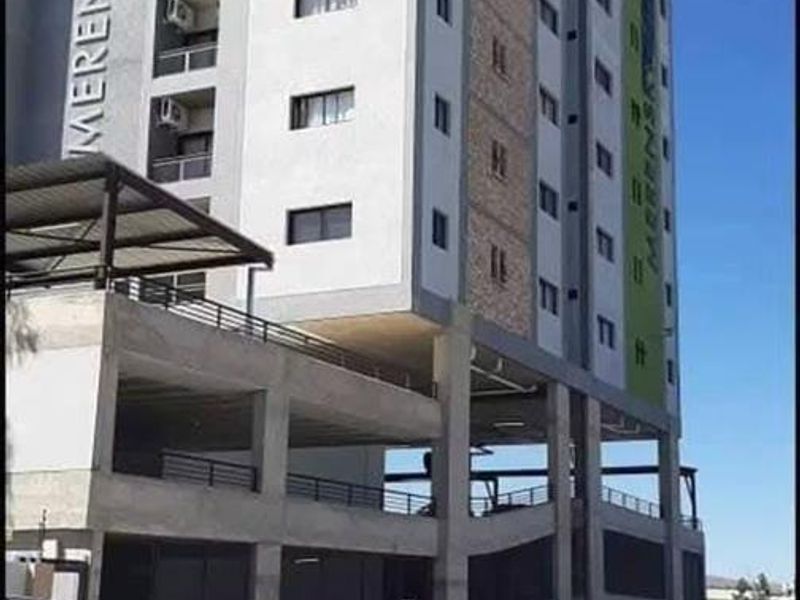 Exterior view of Merensky Tower, a multi-story apartment building featuring modern concrete architecture, integrated balconies, and a covered ground-level parking area.