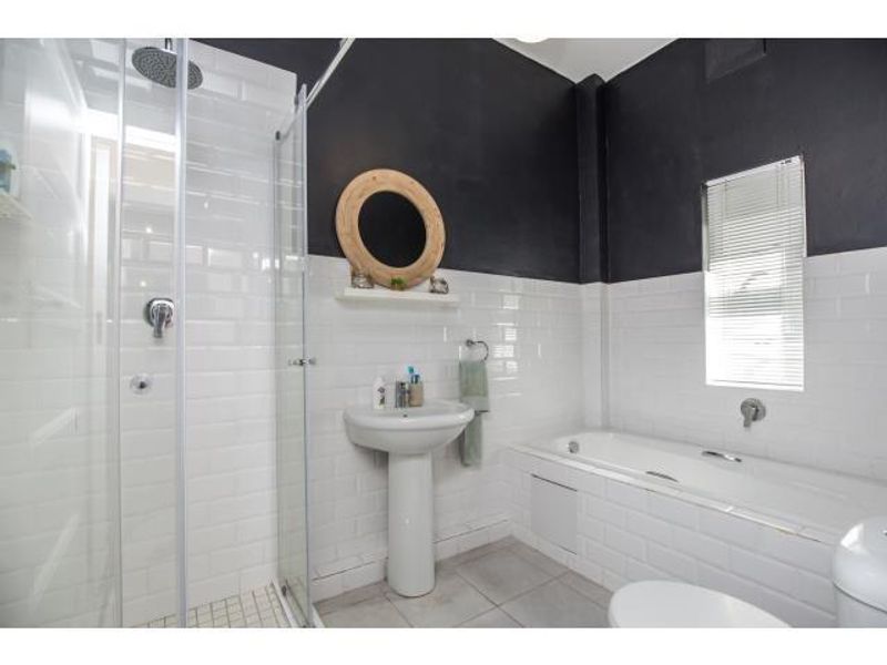 Modern bathroom featuring a pedestal basin, a separate shower enclosure with subway tiling, and a built-in bathtub with a window.
