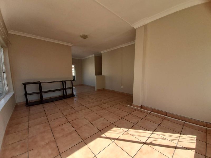 An open-plan living area featuring neutral walls, ceramic floor tiles, and coved cornicing, offering a versatile space ready for personalization.