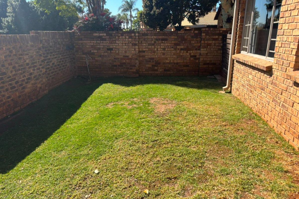 A private rear garden area featuring a brick boundary wall and a small lawn space adjacent to the main house structure.