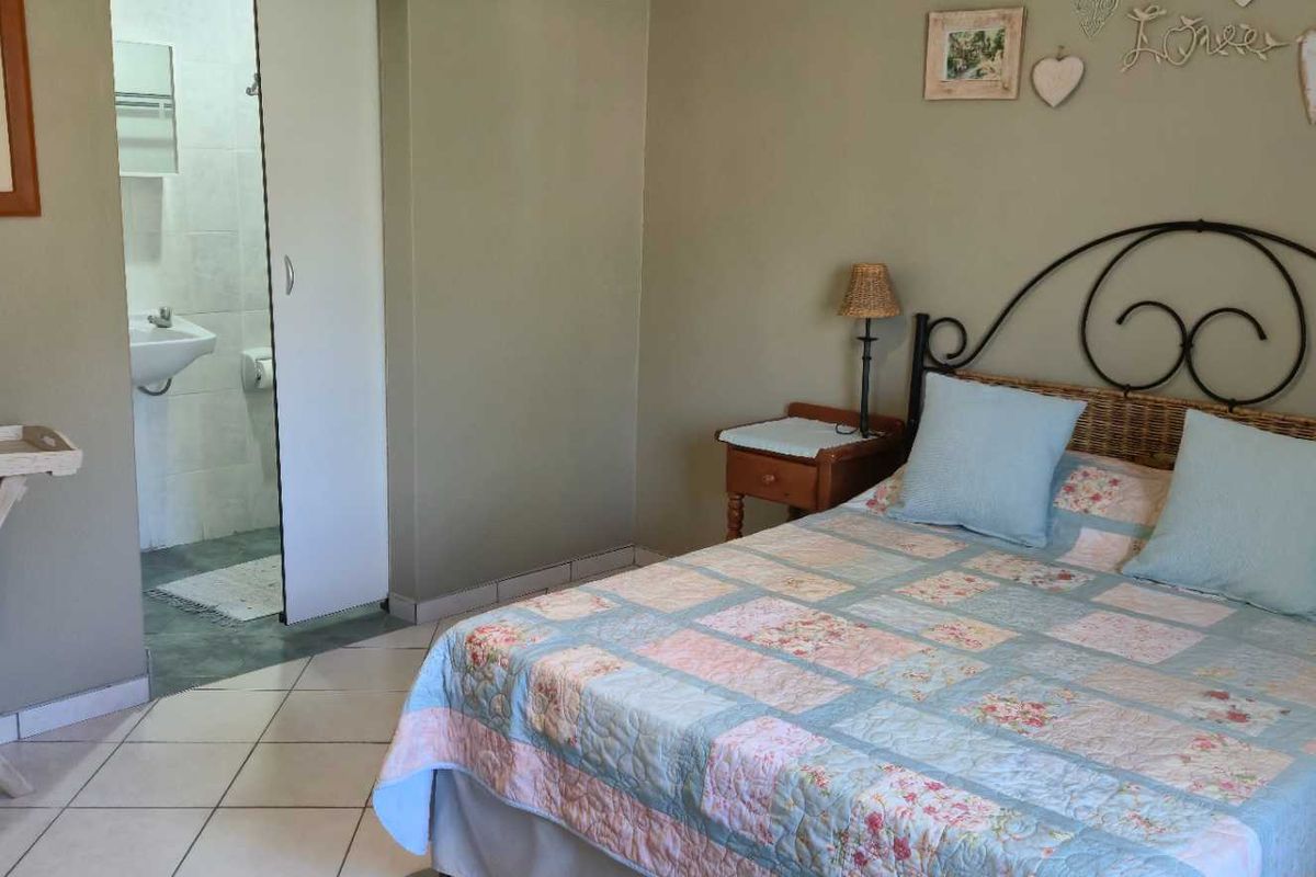 A bedroom featuring tiled flooring and an en-suite bathroom with a basin and toilet.