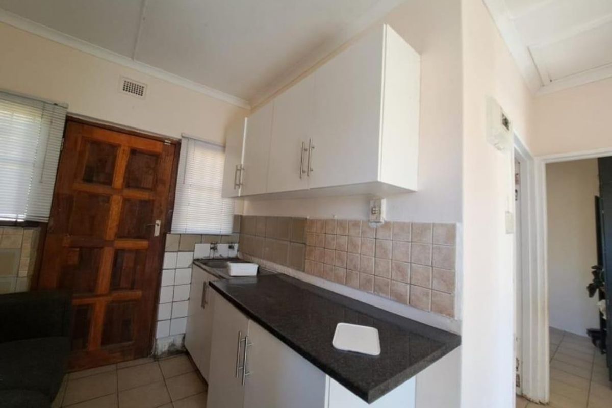 A functional kitchen featuring laminate countertops, built-in cabinetry, and tiled backsplash, offering a practical layout with potential for cosmetic updates.