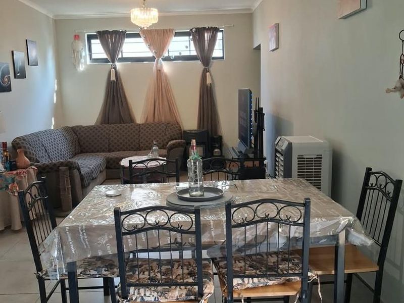Open-plan living and dining area featuring tiled flooring, a split-system air conditioner, and a central chandelier.