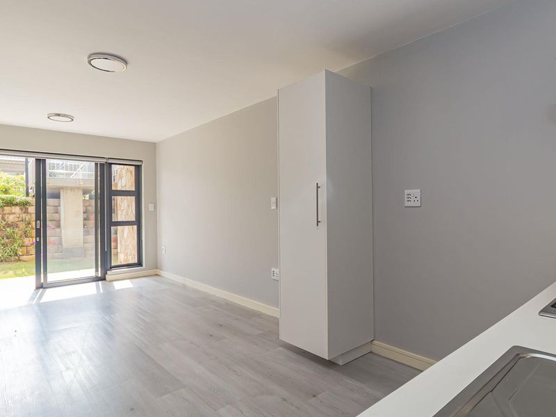 Modern open-plan living area featuring a sleek kitchen with gas hob, extractor fan, and direct access to a private garden through sliding glass doors.