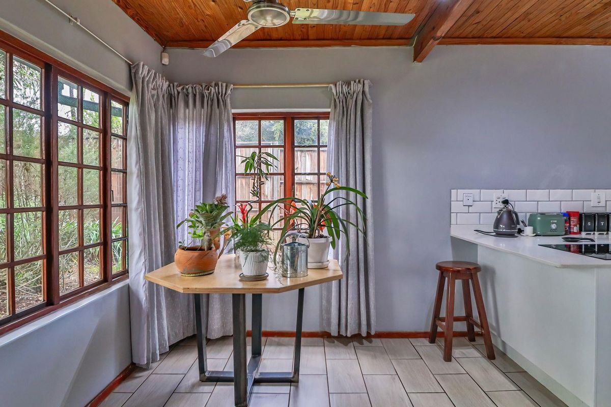 A bright kitchen area featuring a timber ceiling, tiled flooring, subway tile backsplash, and a built-in countertop with an integrated hob.