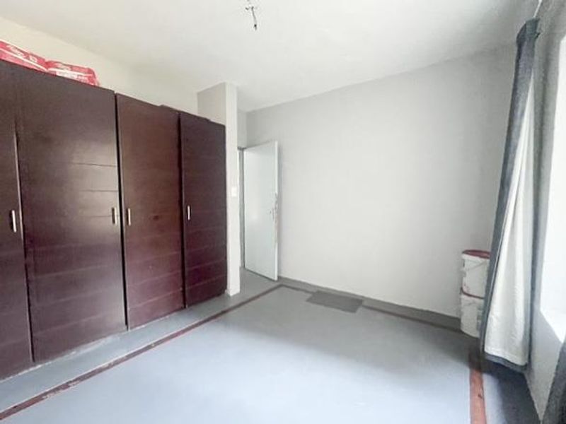 A bedroom featuring built-in cupboards, currently vacant and requiring minor cosmetic updates to the ceiling and flooring.