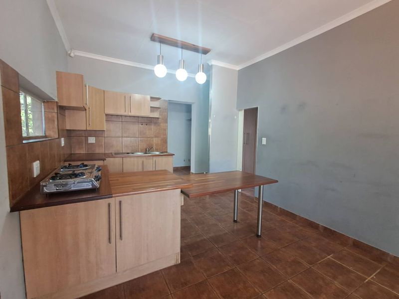 A functional kitchen featuring light wood cabinetry, laminate countertops, a gas hob, and tiled flooring, offering a practical layout for daily use.