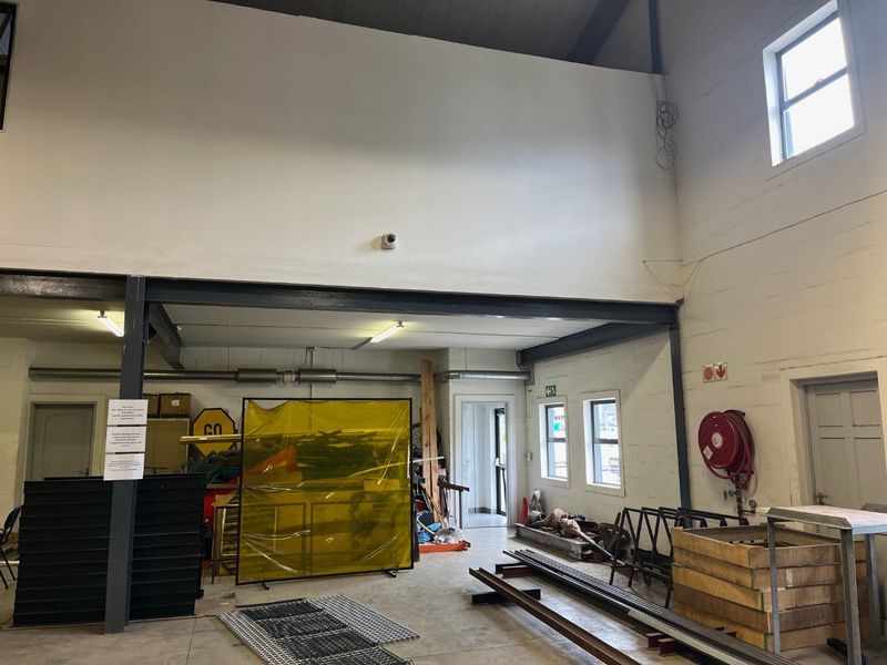 Spacious industrial utility area featuring high ceilings, exposed steel structural beams, concrete flooring, and integrated fire safety equipment.