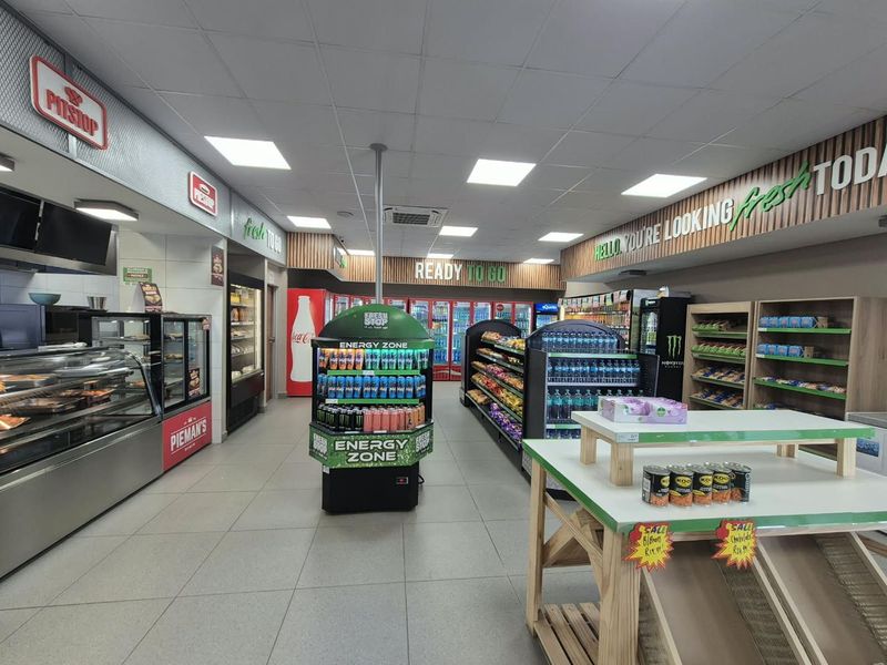 A well-maintained commercial retail space featuring tiled flooring, recessed ceiling lighting, and integrated commercial refrigeration units for food and beverage display.