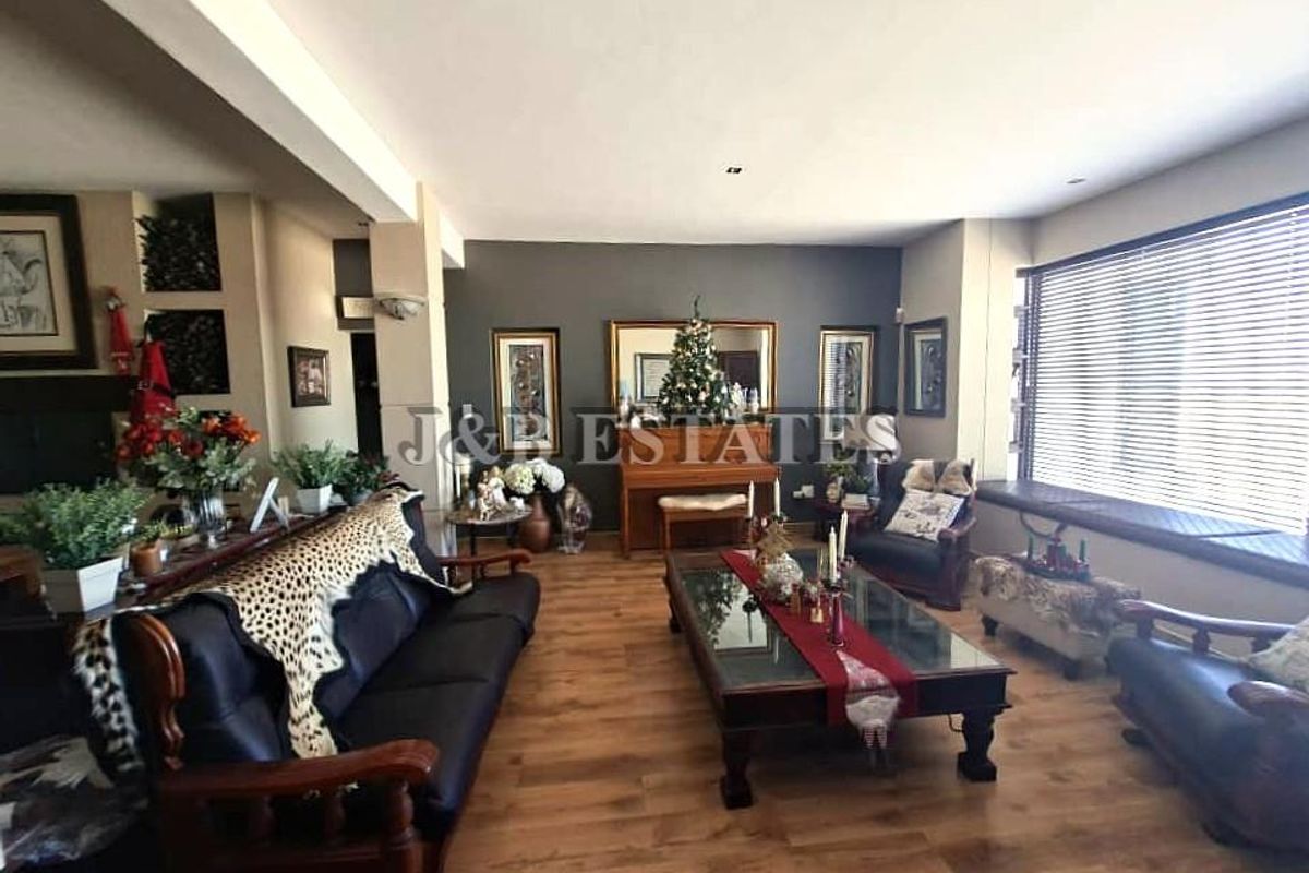 Spacious living room featuring wood-look flooring, recessed ceiling lighting, and a large window with fitted blinds.
