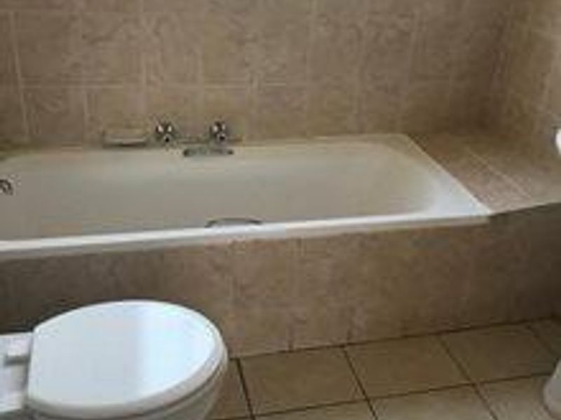 A functional bathroom featuring a built-in bathtub with tiled surround and ceramic floor tiling.