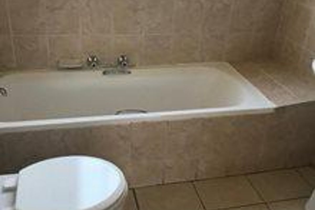 A functional bathroom featuring a built-in bathtub with tiled surround and ceramic floor tiling.