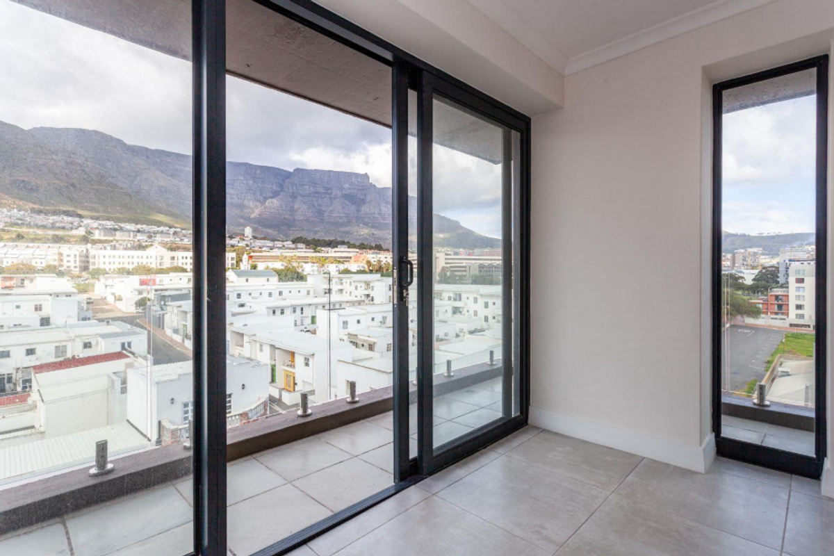 A bright living area featuring large sliding glass doors that open onto a balcony with expansive mountain and city views.