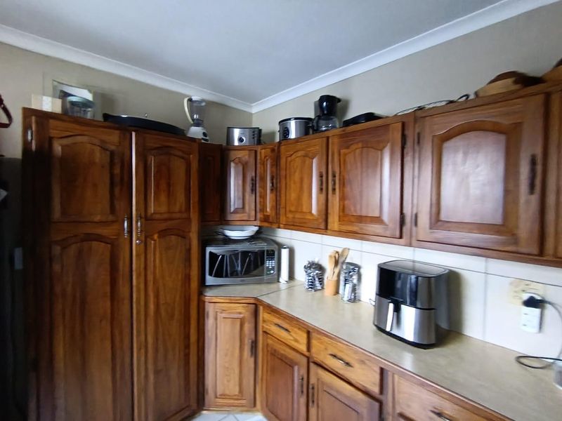 A functional kitchen featuring traditional wooden cabinetry, laminate countertops, and a tiled backsplash, offering a classic aesthetic with potential for modern updates.