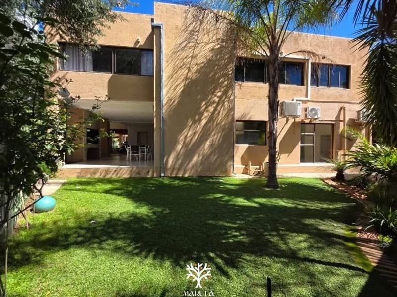 Rear view of a two-story house featuring a stucco facade, a covered patio area, and a well-maintained garden.
