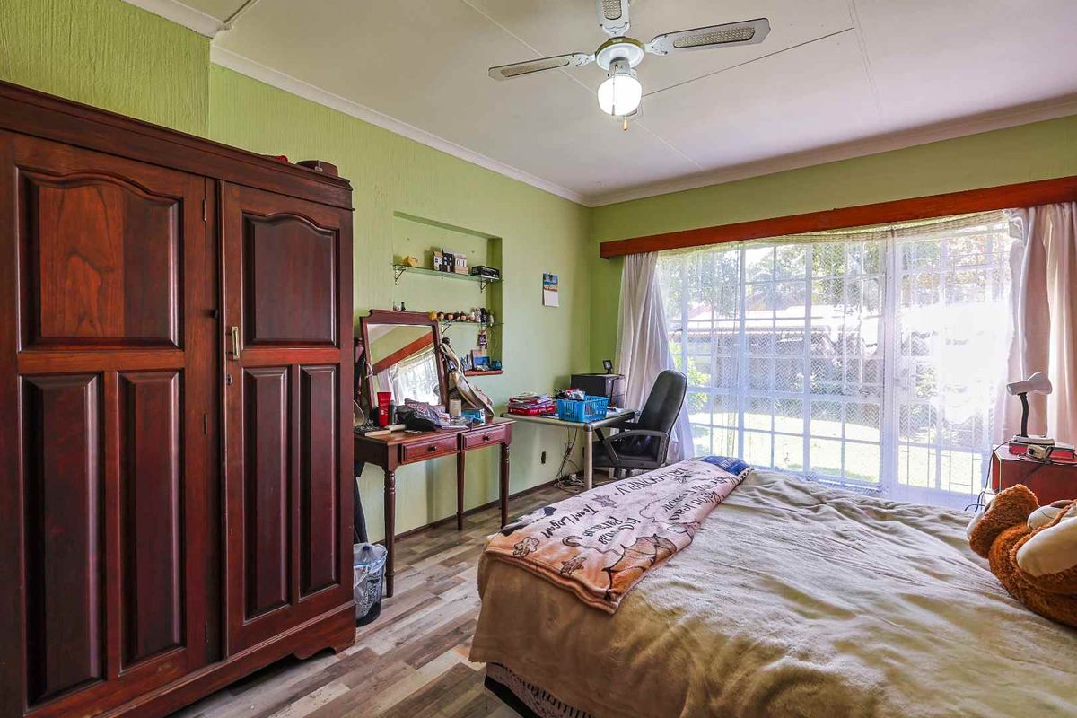 A bedroom featuring wood-look flooring, a ceiling fan, and large sliding glass doors providing natural light and access to the exterior.