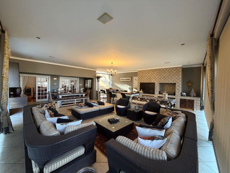 Spacious open-plan living area featuring tiled flooring, a large built-in fireplace, and direct access to adjacent rooms through classic french doors.