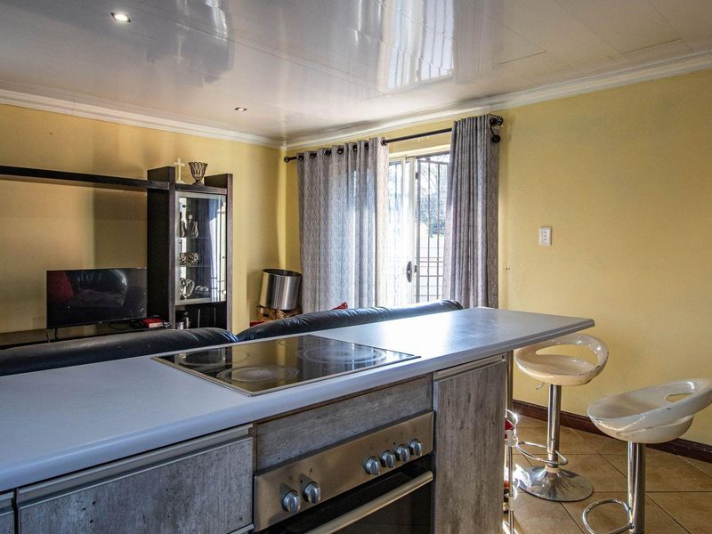 Open plan living area featuring a kitchen island with integrated electric hob and oven, leading to a patio through glass sliding doors.