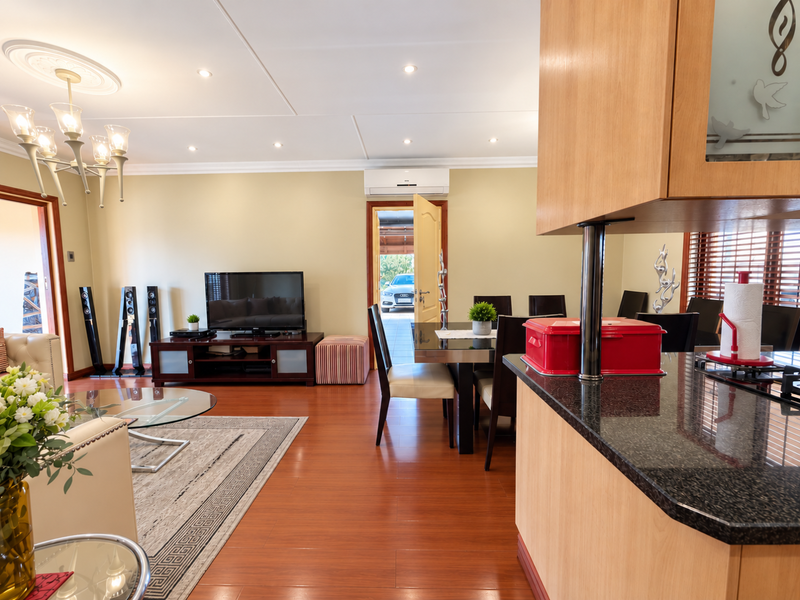 Spacious open-plan living and dining area featuring laminate flooring, recessed lighting, and a functional kitchen with granite countertops and wooden cabinetry.