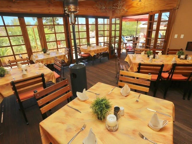 A spacious, enclosed patio area featuring timber decking and extensive timber-framed glass windows, providing a bright and inviting atmosphere for dining.