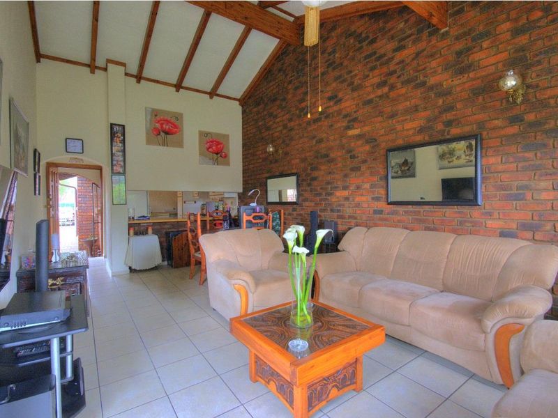 Spacious open-plan living area featuring a vaulted ceiling with exposed timber beams and a prominent exposed brick feature wall.
