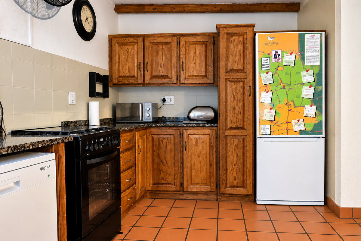 A functional kitchen featuring traditional wooden cabinetry, granite countertops, tiled flooring, and a freestanding oven, accented by an exposed timber ceiling beam.