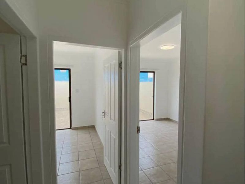 A bright hallway with tiled flooring providing access to multiple rooms, featuring neutral finishes and clean architectural lines.