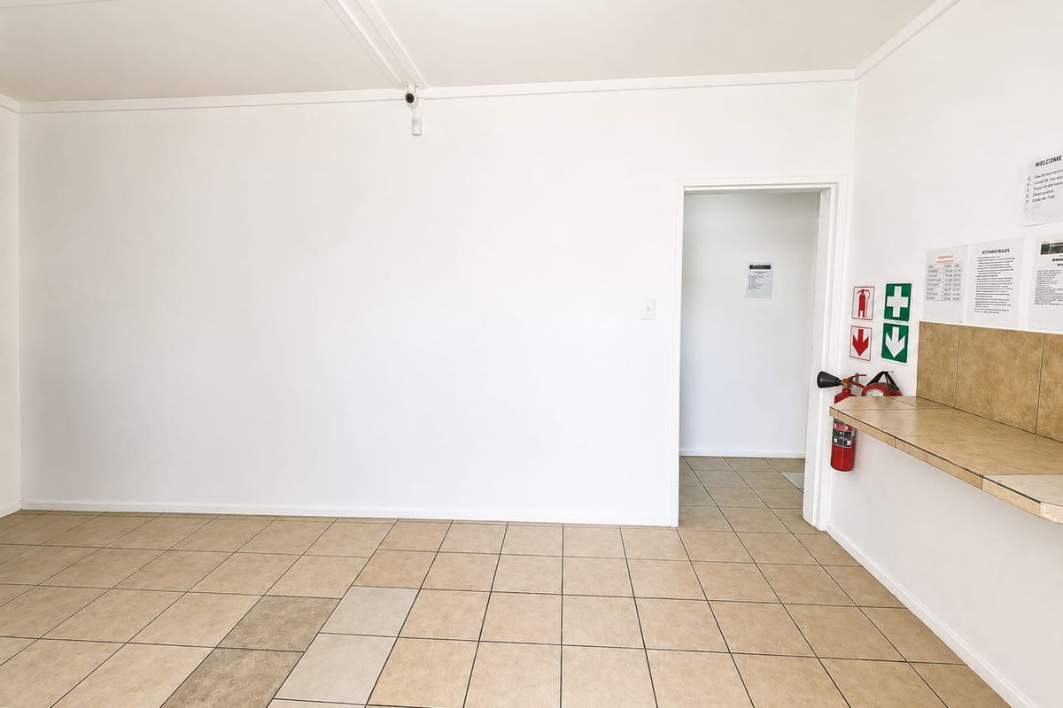 A clean, empty utility space featuring tiled flooring, a fixed counter, and safety equipment including a fire extinguisher and security camera.