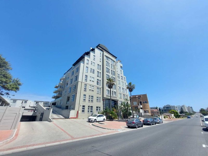 Exterior view of the Grasso Heights apartment building, featuring a paved driveway, secure access, and multi-level balconies.