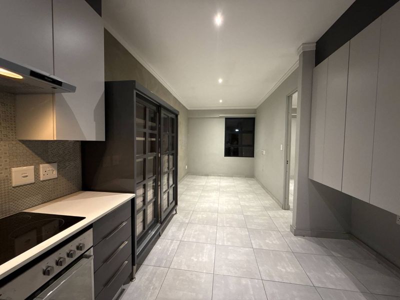 Modern kitchen featuring sleek built-in cabinetry, integrated appliances, and neutral tiled flooring, offering a clean and functional space.