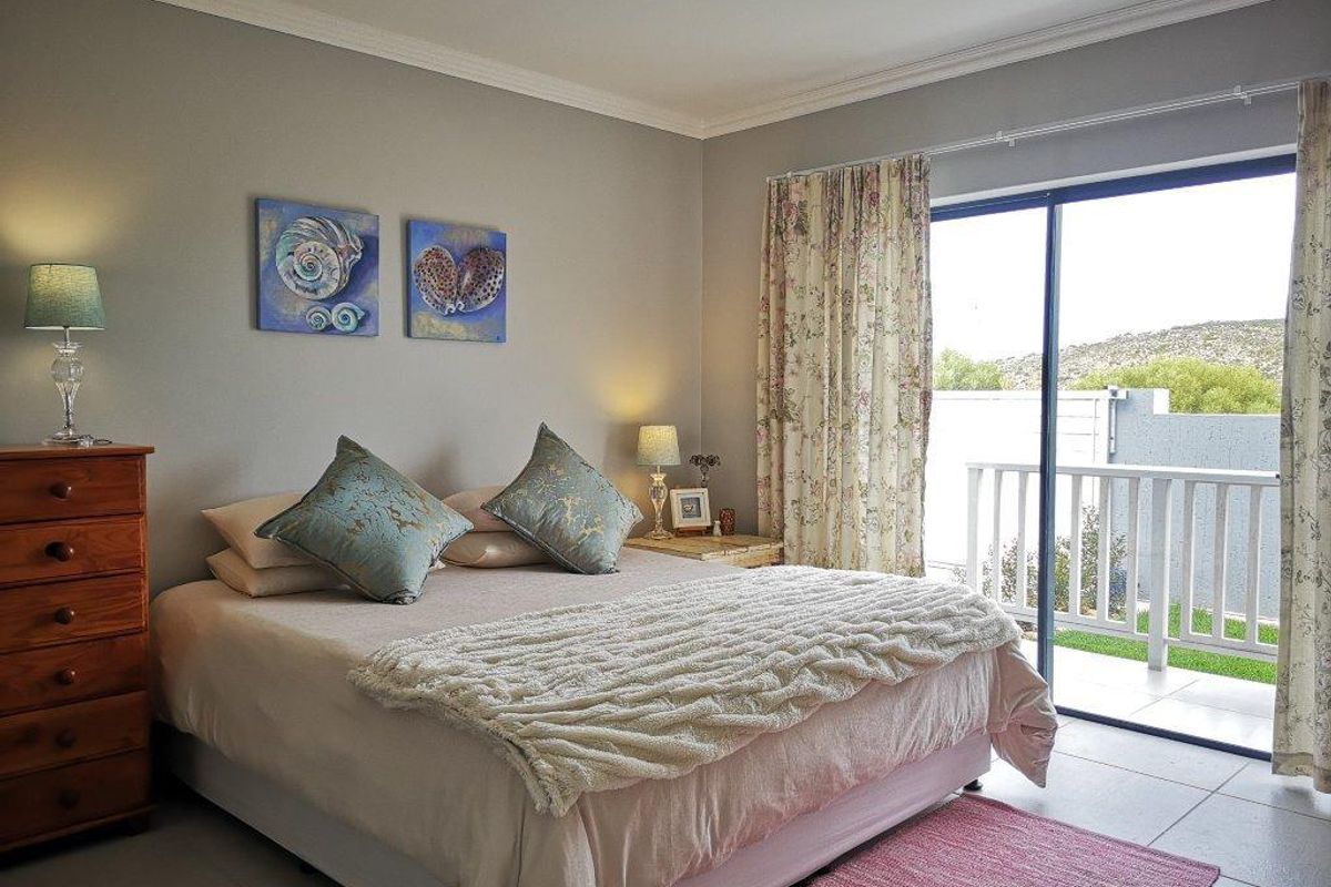 A well-maintained bedroom featuring tiled flooring, neutral wall tones, and a sliding glass door providing direct access to an outdoor balcony area.