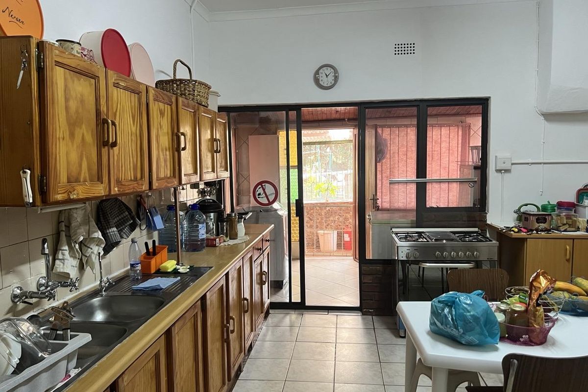 A functional kitchen featuring wooden cabinetry, a double sink, a gas stove, and direct access to an enclosed patio area.