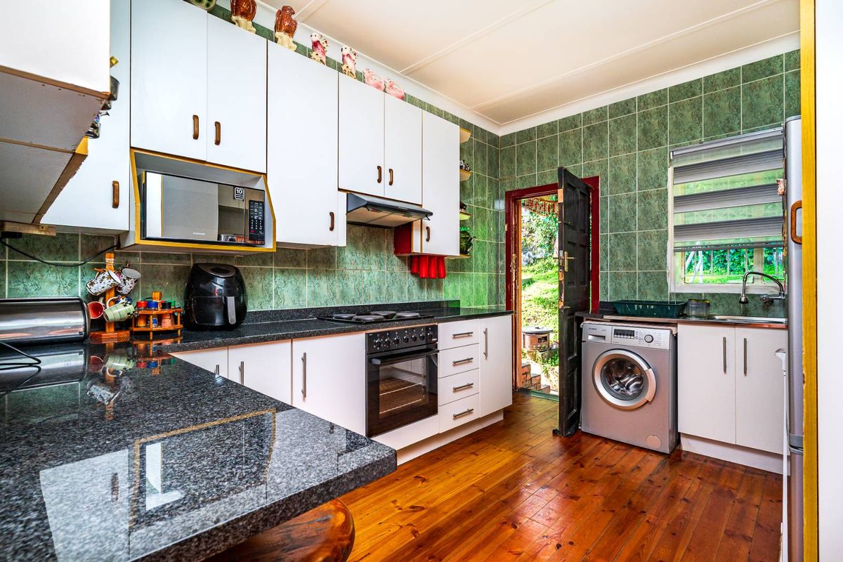 Functional kitchen featuring granite countertops, built-in oven, hob, and extractor fan, with direct access to the rear garden area.