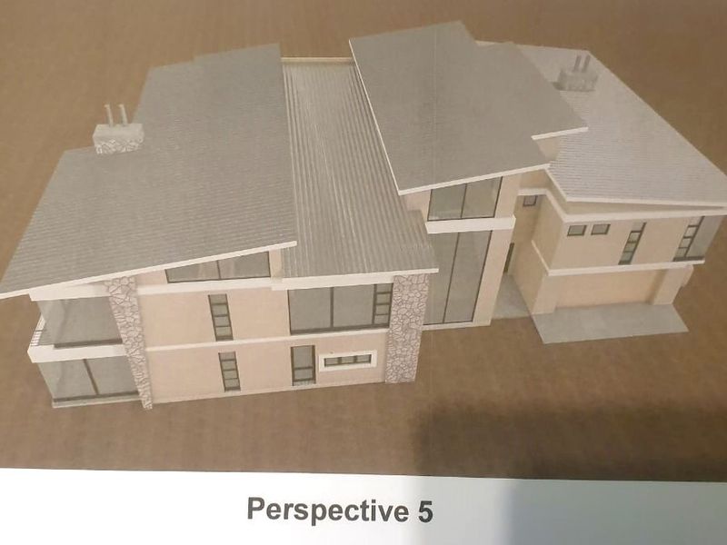 A scale architectural model showing the exterior design of a modern multi-level house with stone accents and a pitched metal roof.