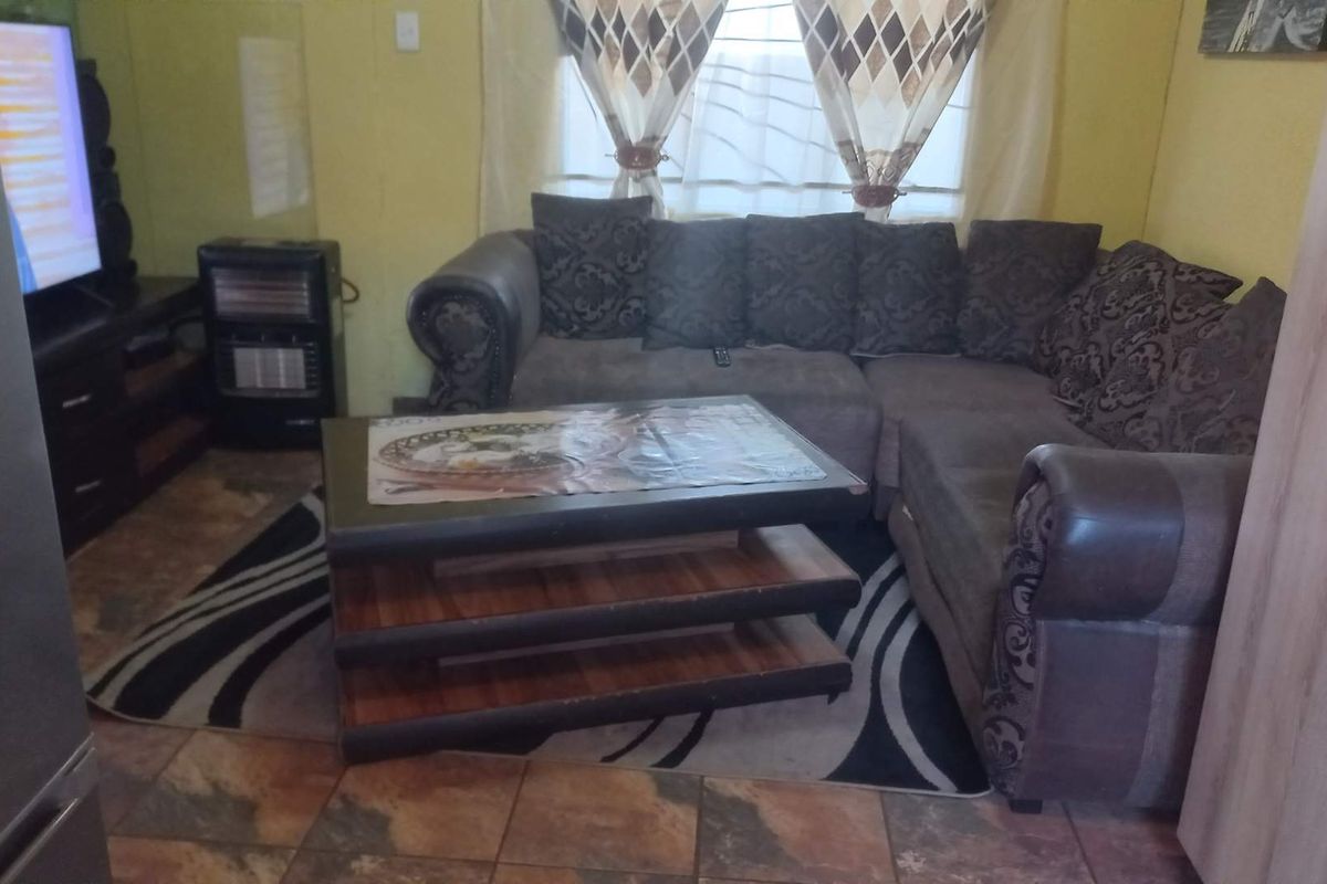 A living room area featuring tiled flooring and a window, providing a functional space for relaxation.