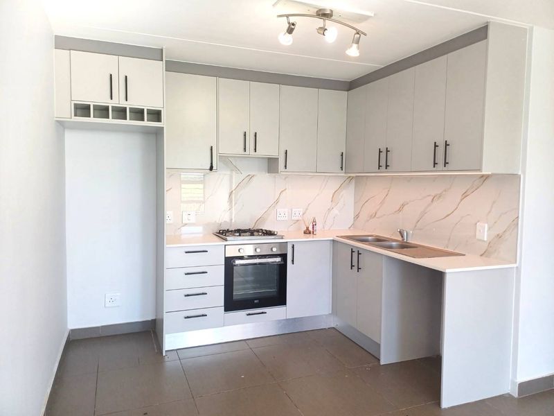 Modern kitchen featuring light grey cabinetry, marble-look splashback, built-in oven, gas hob, and double sink with tiled flooring.