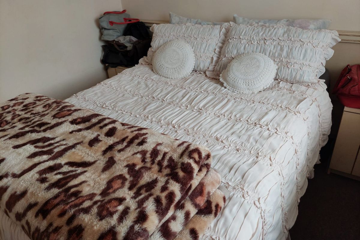 A standard bedroom space featuring neutral wall finishes and carpeted flooring.